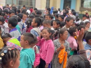 Niños reunidos a la salida de la escuela con coloridos uniformes en un acto escolar en China.