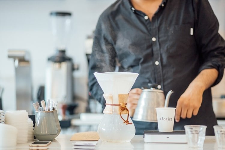 Barista preparing coffee at a Chemex brewing station in a modern cafe