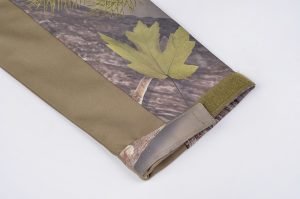 Water-resistant outdoor jacket with camouflage leaf print and adjustable Velcro cuffs. Perfect for workwear or outdoor activities, providing durability and comfort in various environments.