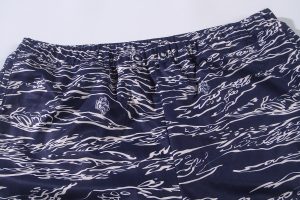 Comfortable navy blue shorts with a white abstract lion and wave pattern, featuring elastic waistband and button closure, ideal for casual wear or beach outings.