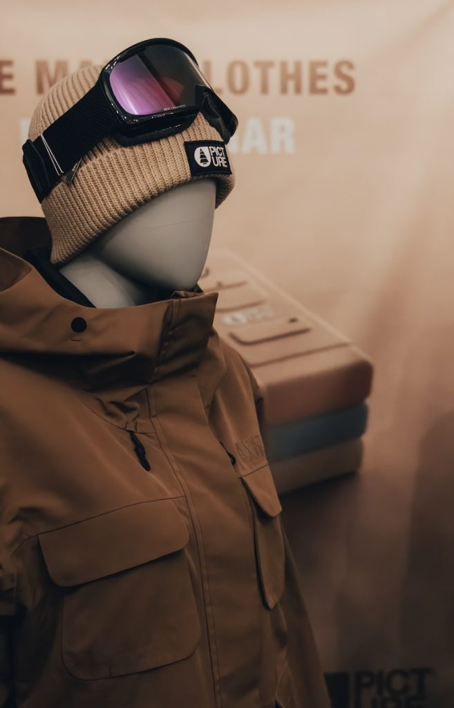 Hochwertige Wintersicherheitsjacke mit mehreren Taschen, Farbe beige und verstellbaren Funktionen, kombiniert mit einer Mütze und einer Brille für Arbeit oder Sport im Freien. Perfekt für den Schutz vor kaltem Wetter.
