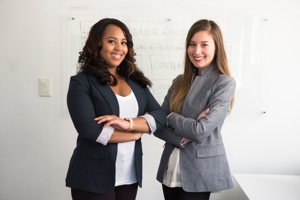 Elegant women wearing corporate blazers in a professional office setting for business or team meeting.