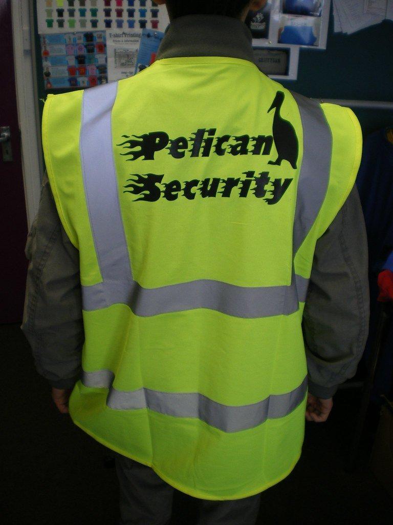 High-visibility safety vest with "Pelham Security" logo and mascot silhouette, worn by security personnel, emphasizing custom workwear for security and safety teams.