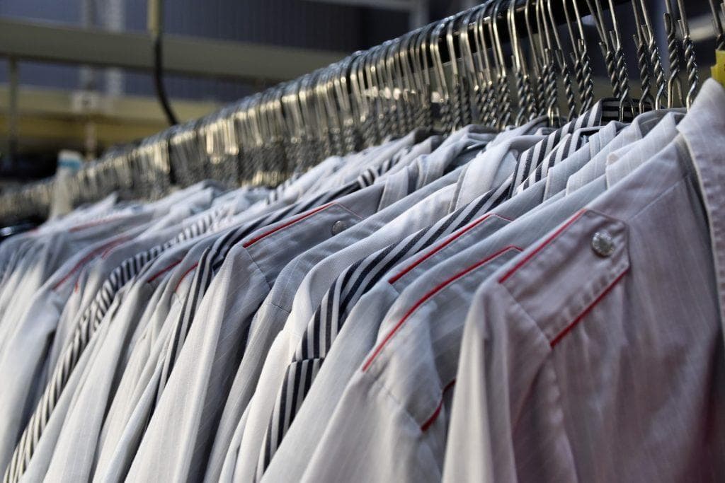 Bright white and patterned work uniforms hanging on metal racks at a manufacturing facility in China.