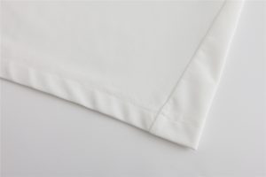 White custom work uniforms fabric close-up with stitching detail for professional clothing manufacturing.