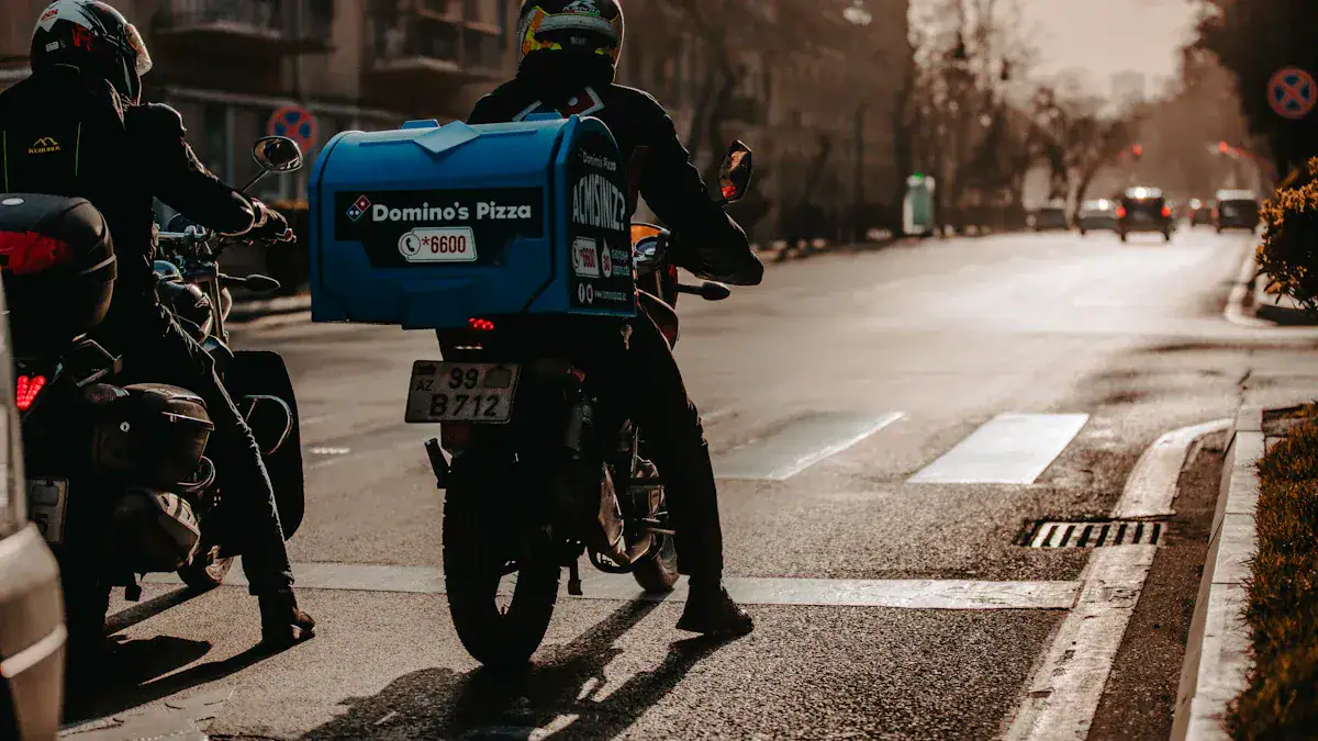 Domino's Pizza delivery motorcycle on city street with riders in protective gear and uniforms.