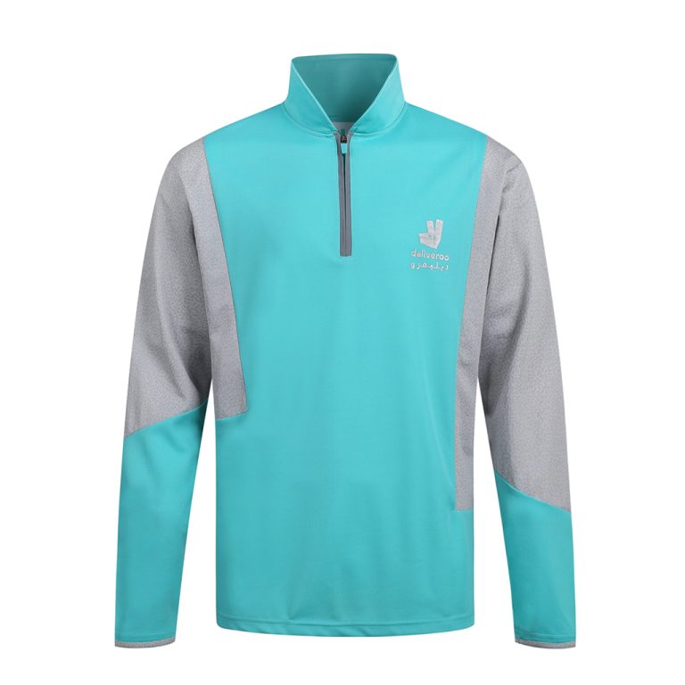 Chaqueta deportiva personalizada de color turquesa y gris brillante con cremallera en un cuarto, diseñada para trabajadores de servicios de reparto, con logotipo de la marca y cómodo corte atlético.