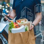 Fresh vegetable meal in a paper bag held by a delivery worker wearing a work uniform on a city street.