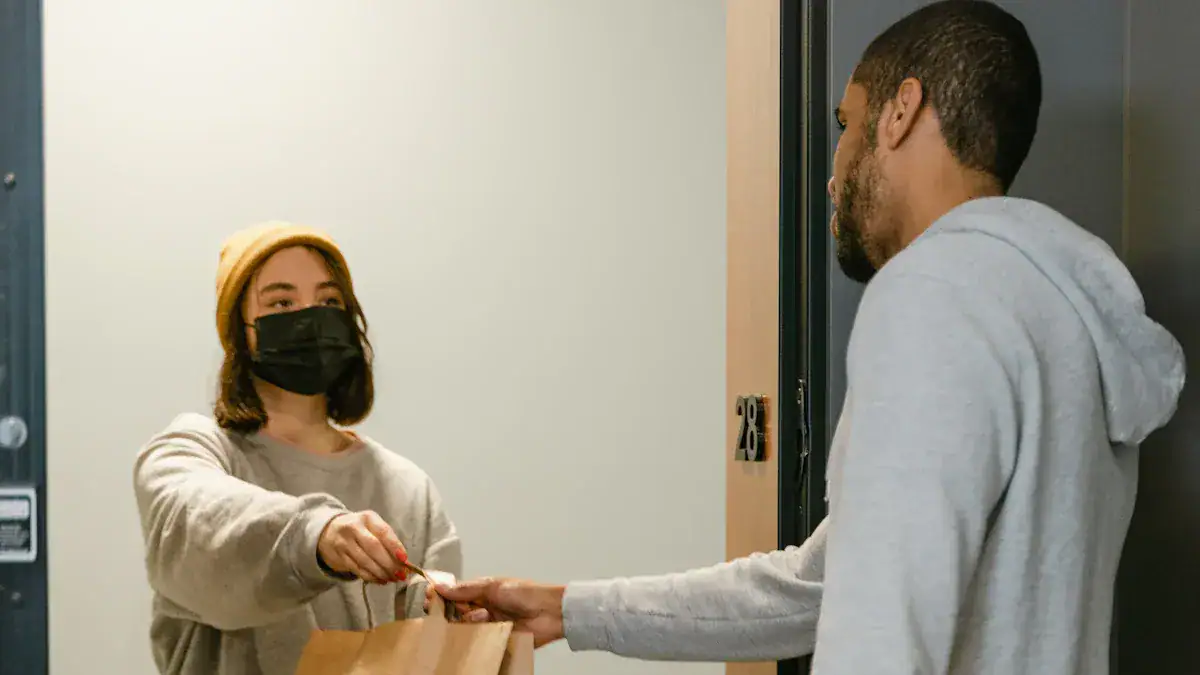 Comfortable gray casual clothing with a black face mask, woman receiving a paper bag from man in a hoodie at apartment door.