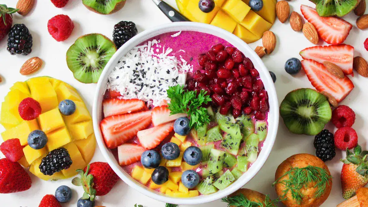 Fresh colorful fruit smoothie bowl with assorted berries, mango, kiwi, and coconut, surrounded by fresh fruit slices and nuts for a vibrant, healthy breakfast or snack.