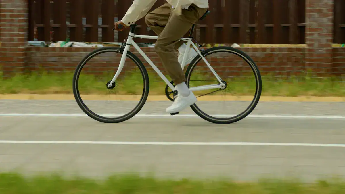 One person riding a white bicycle on a paved road wearing casual clothing and white shoes.
