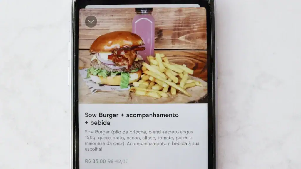 Grilled cheeseburger with bacon, lettuce, tomato, pickles, and mayonnaise served with French fries on a rustic wooden table.