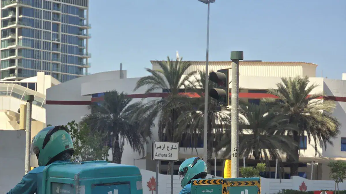 High-angle view of street with palm trees, traffic lights, and building, featuring workers on motorcycles in safety gear in Dubai.