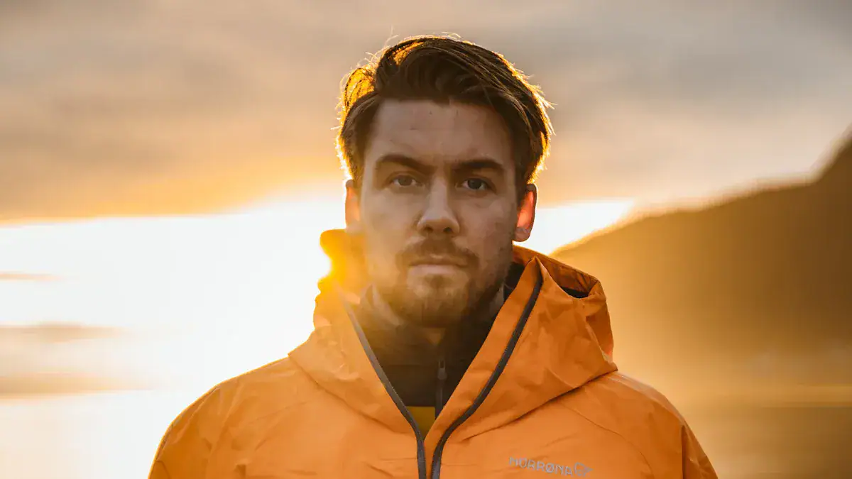 Men wearing orange waterproof safety jackets outdoors at sunset.
