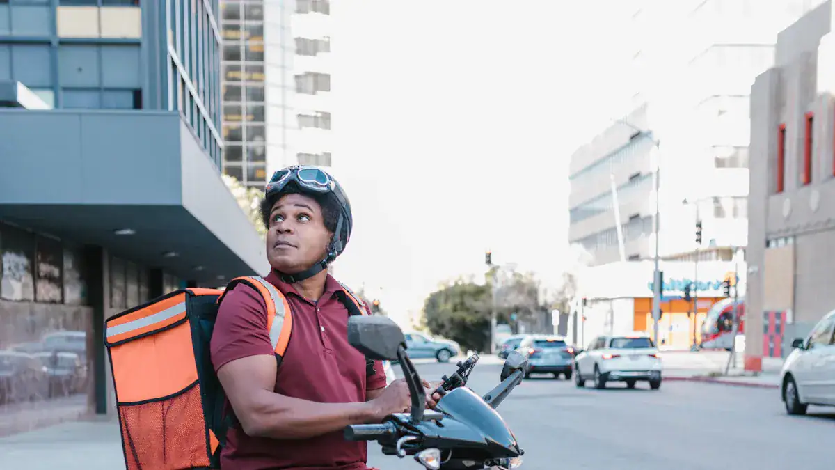 Helmeted delivery rider with a thermal backpack looking up in an urban city setting showcasing custom workwear uniforms from China manufacturer Sha.