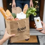 Fresh groceries in a food delivery bag being handed to a customer using a mobile app at the doorstep.