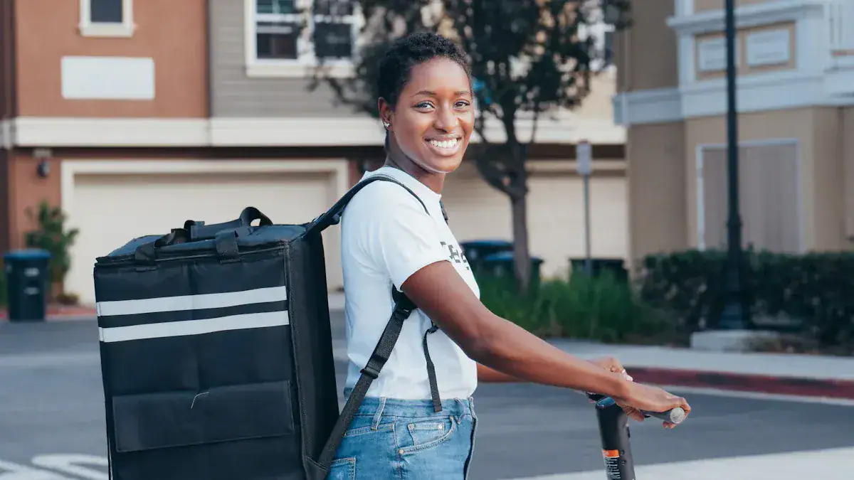 Fast food delivery woman smiling with a large insulated delivery bag, ready to serve, outdoors in a residential neighborhood.