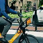 High-quality bike courier in casual uniform riding an electric bike in urban city street.