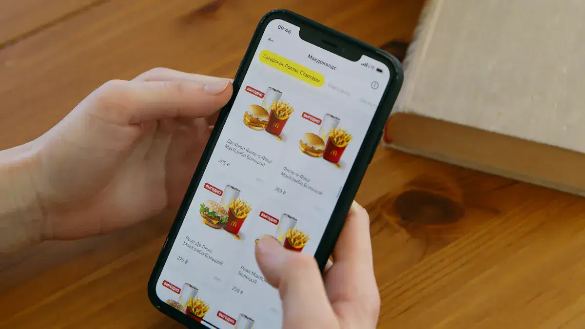 Bright smartphone screen displaying fast food menu with McDonald's burgers and fries, held in a person's hand over a wooden table.