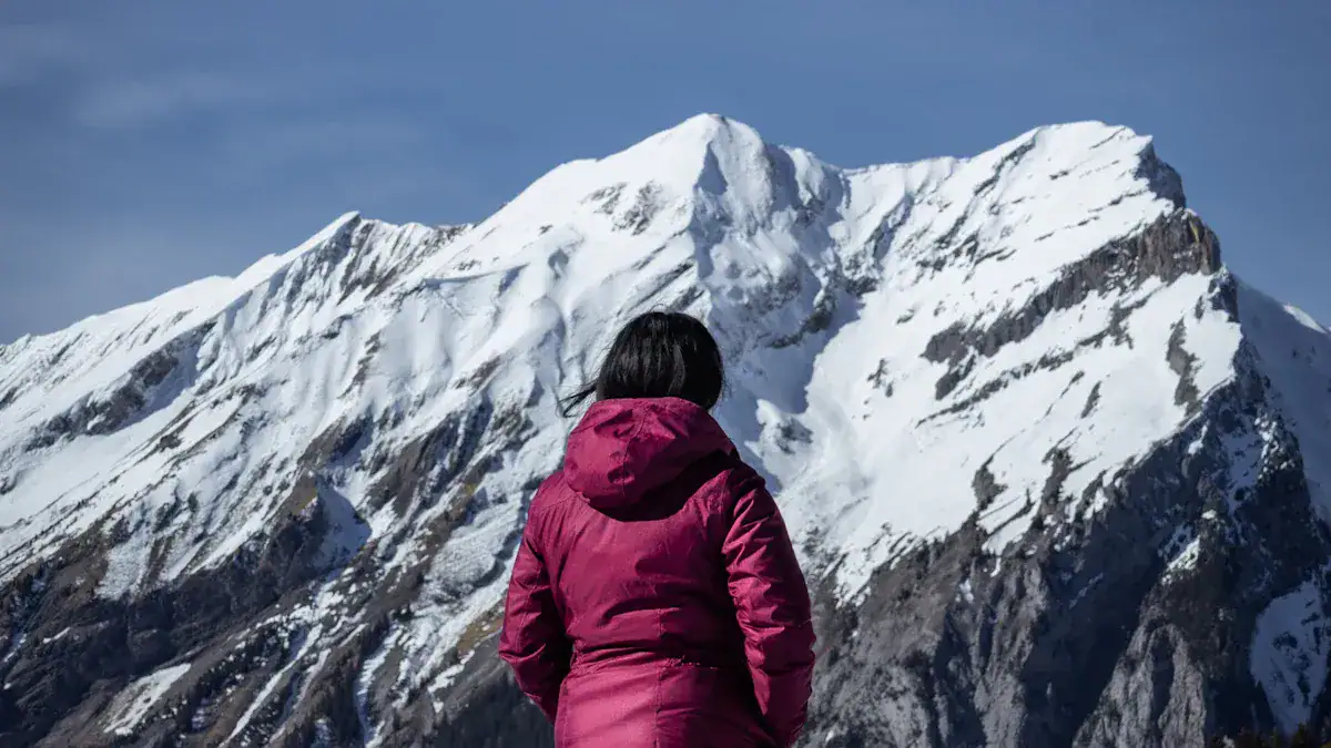 Warm outdoor winter jacket worn during mountain expedition against snow-covered peaks.