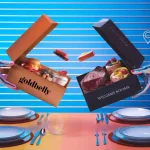 Colorful cake boxes being exchanged over a dinner table with plates, forks, and knives, against a vibrant, digitally-inspired background with transportation icons.