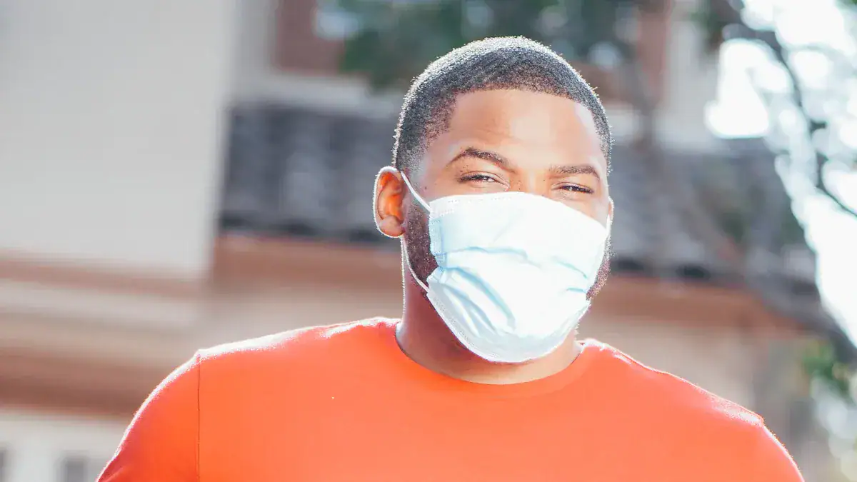 Face of a young man wearing a white protective face mask outdoors, sunlight illuminating his face, with a blurred urban background.
