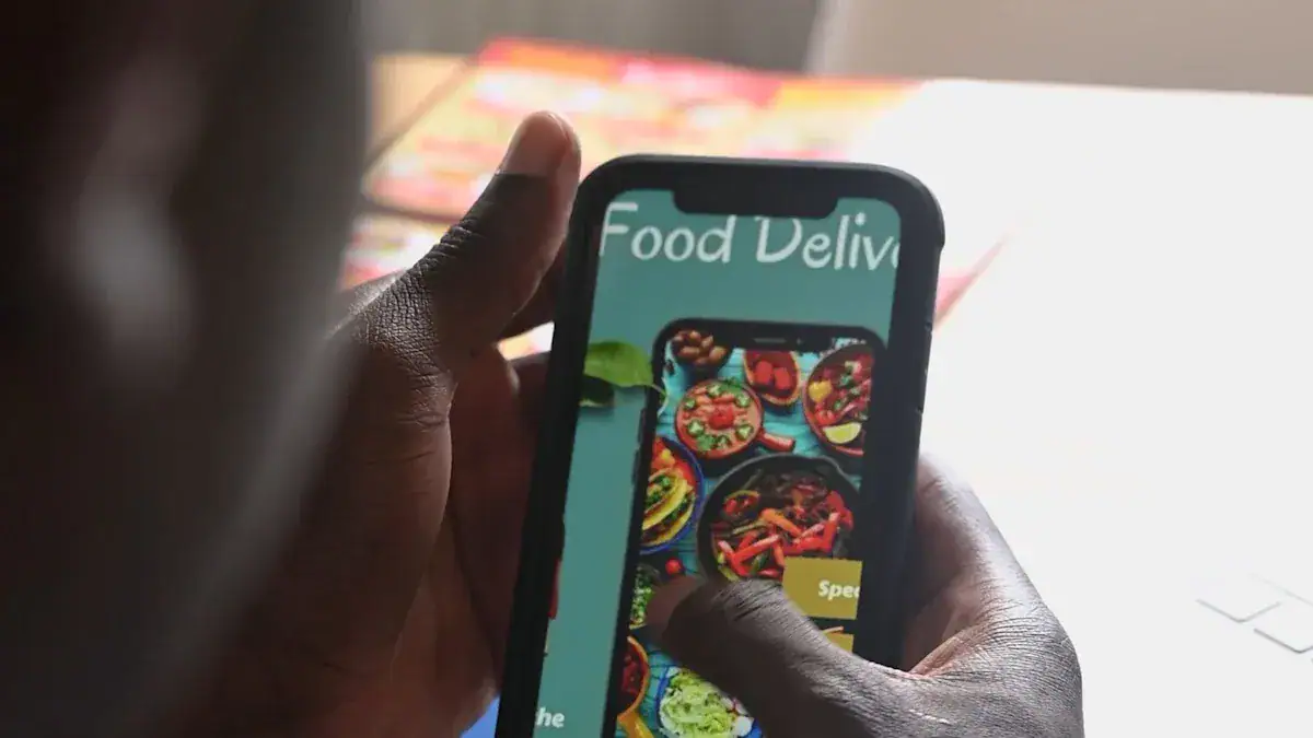Food delivery mobile app display on smartphone screen showcasing colorful dishes, digital food menu, and online ordering interface, with focus on user interaction and modern convenience.