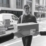 Delivery person exchanging a package outside a building, showcasing professional uniform clothing suitable for workwear manufacturers.