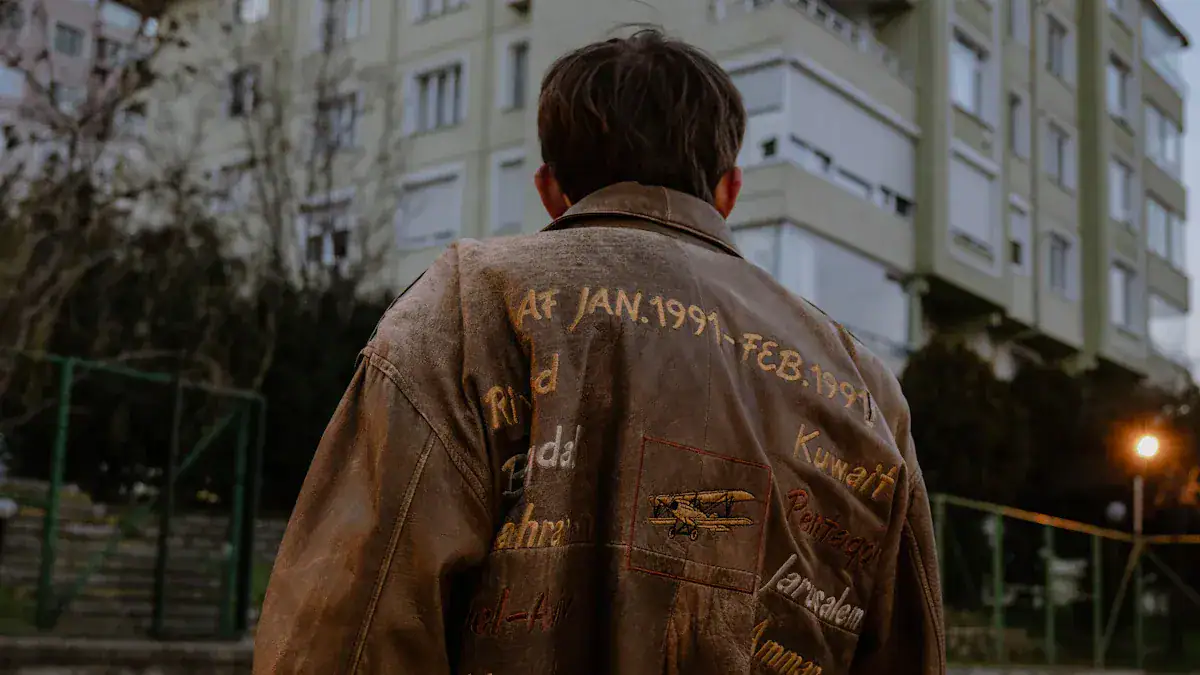 Custom embroidered leather jacket with patches and embroidery representing different locations and dates, worn by a person outdoors near a building.