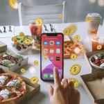 Free, artificial coins falling around a person interacting with a smartphone on a table with food and drinks, representing online shopping and digital transactions.