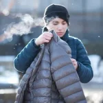 Warm insulated work jacket being inspected outdoors in cold weather by a worker.