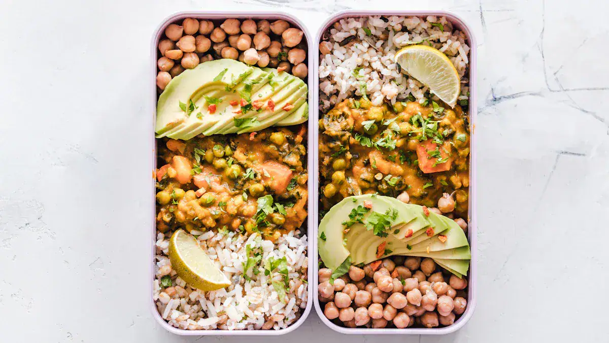 Fresh vegan chickpea and rice meal prep bowls with avocado slices and lime wedges on white marble surface.