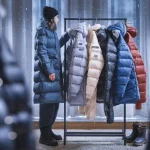 Down jackets on display at a winter clothing store, showcasing custom workwear and uniforms for cold weather, in a professional retail environment.