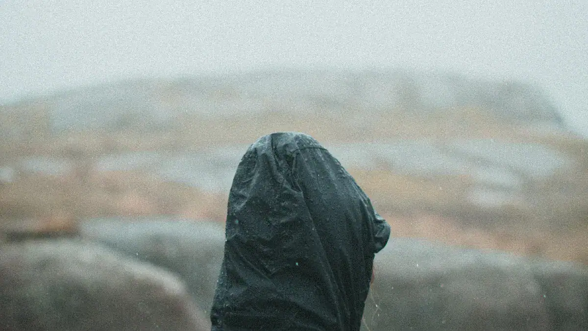 Rain-soaked black waterproof boot in a stormy outdoor environment.