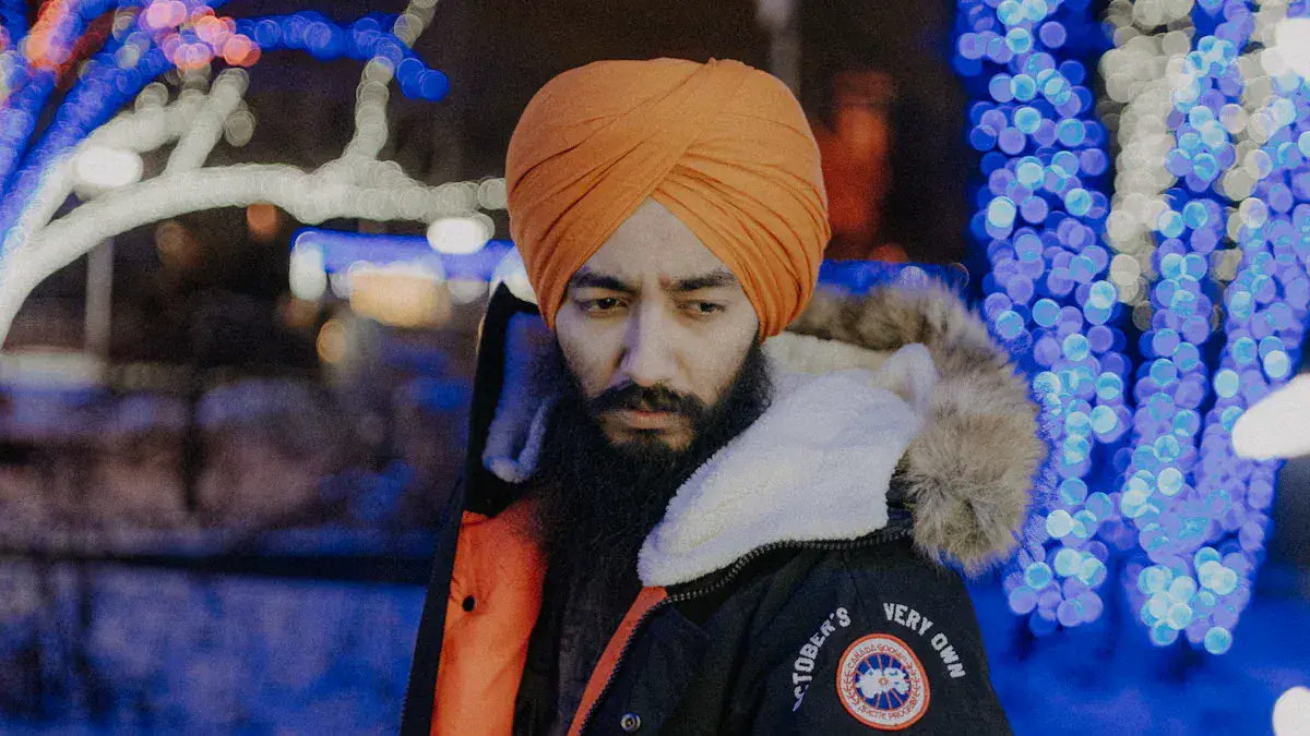 Warm winter jacket with fur-lined hood worn by a man with a bright orange turban, outdoor festive lights background.