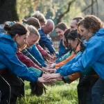 Blue waterproof work jackets worn by a group of diverse people participating in an outdoor team activity in a park outdoor workwear, team building, waterproof clothing, active lifestyle, group cooperation, corporate event, outdoor team sport, rain gear, community gathering, uniform clothing, uniform manufacturer, custom workwear, outdoor apparel China manufacturer.