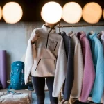 High-quality custom clothing uniforms displayed on a rack in a manufacturing setting, showcasing various colors and styles for corporate or outdoor use.