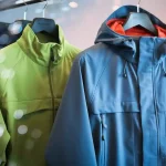 Bright green and navy waterproof jackets displayed on hangers in a retail environment, designed for outdoor wear and rain protection, showcasing customizable workwear options from a China manufacturer.