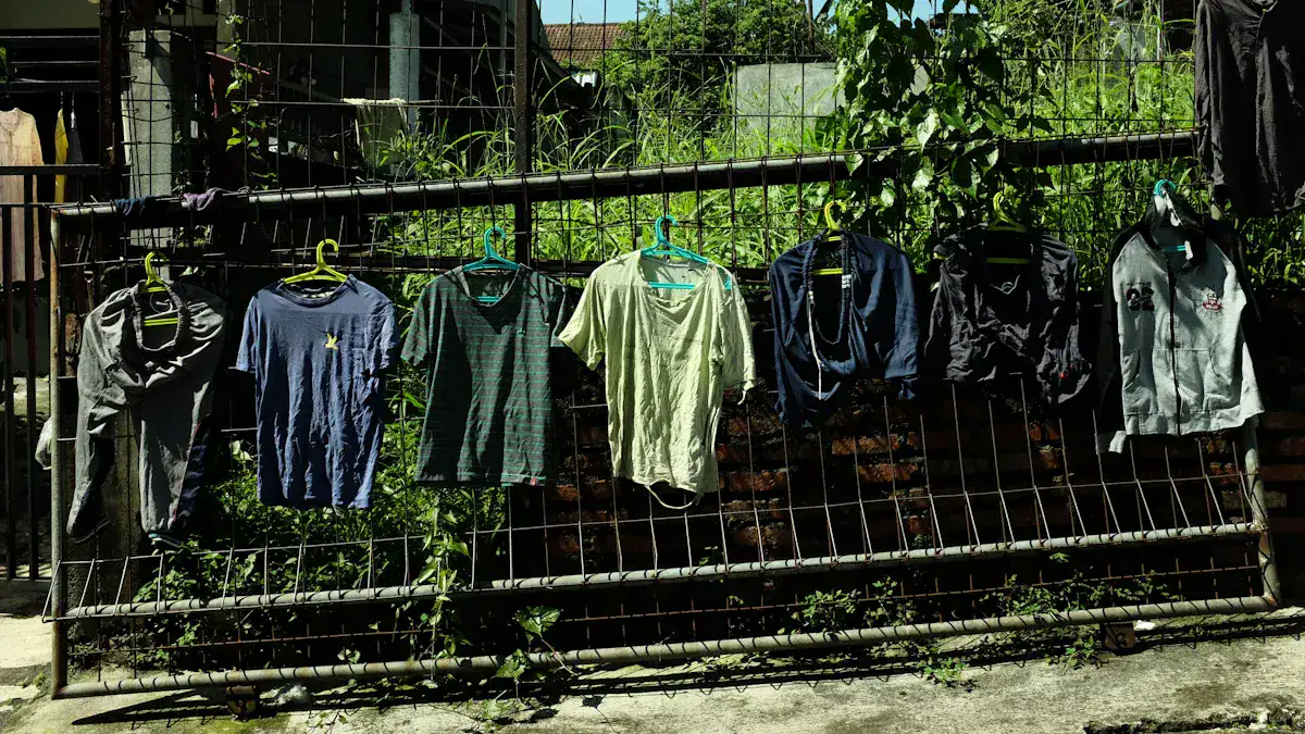 Brightly colored casual and sports t-shirts hanging on a metal fence outdoors, showcasing custom clothing options for workwear and uniforms.