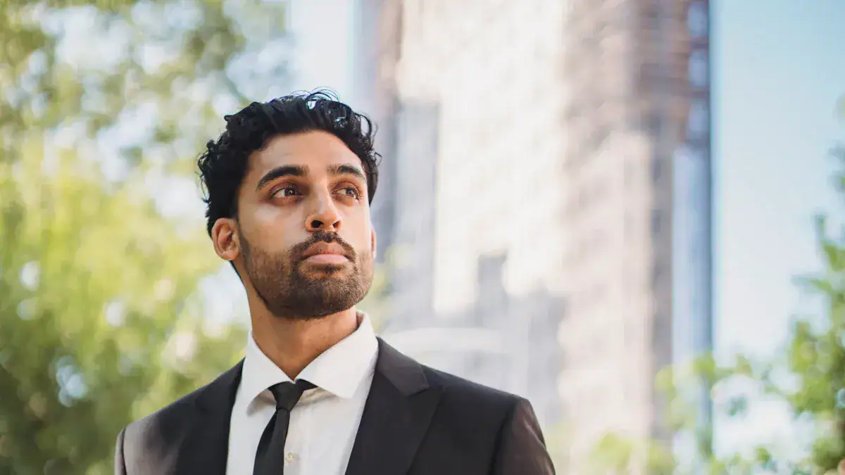 Men's professional black suit and white shirt for business wear, outdoor setting with green trees and blurred building background.