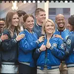 Airport staff wearing coordinated blue and black custom uniforms, smiling and engaging together.