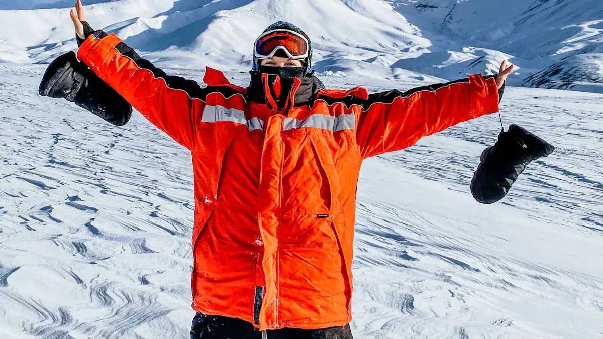 Warm orange winter jacket with reflective strips, snow gloves, and protective gear on a snowy mountain landscape. Perfect for cold weather outdoor activities like skiing or snowboarding.