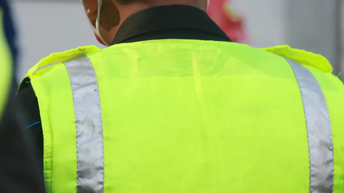 High-visibility safety vest worn by a worker for industrial and construction site safety, featuring reflective strips for enhanced visibility in low light conditions.