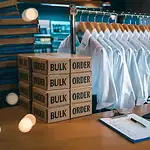 Custom workwear shirts hanging on a rack in a manufacturing facility.