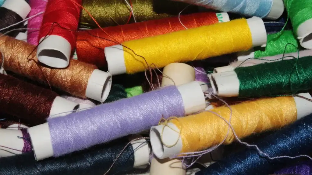 Colorful sewing threads on white spools, showcasing vibrant textile and garment manufacturing materials in various shades for custom clothing and uniforms.