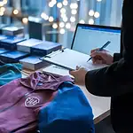 Custom workwear uniforms displayed on table at clothing manufacturing facility in China, with fabric samples and design planning.