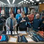 Premium custom clothing uniforms displayed at a trade show booth, showcasing diverse fabrics, colors, and designs for manufacturing in China.