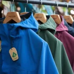 Brightly colored waterproof rain jackets hanging on a clothing rack outdoors, showcasing custom-designed workwear uniforms from a China-based manufacturer.