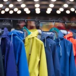 Brightly colored work jackets hanging on a rack, representing custom workwear uniforms for various industries like construction, healthcare, and outdoor activities.