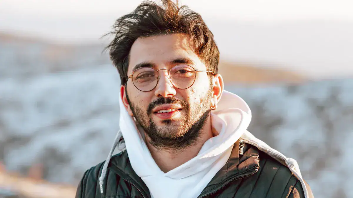 Stylish young man wearing sunglasses and casual hoodie outdoors with blurred background.